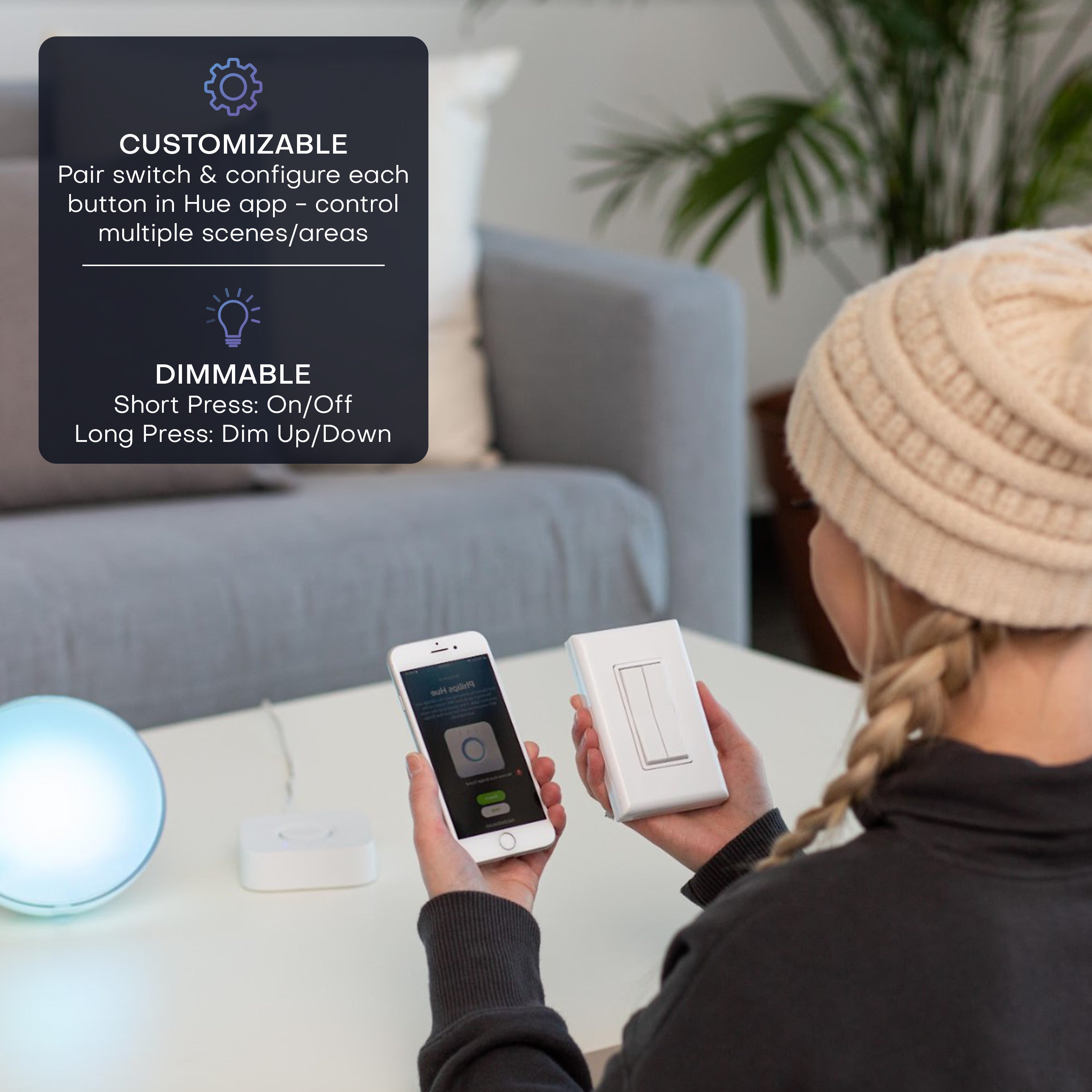 A person holds a dual rocker smart switch and a phone with the Philips Hue app in a living room setting, with an informational overlay explaining customization and dimmable features.